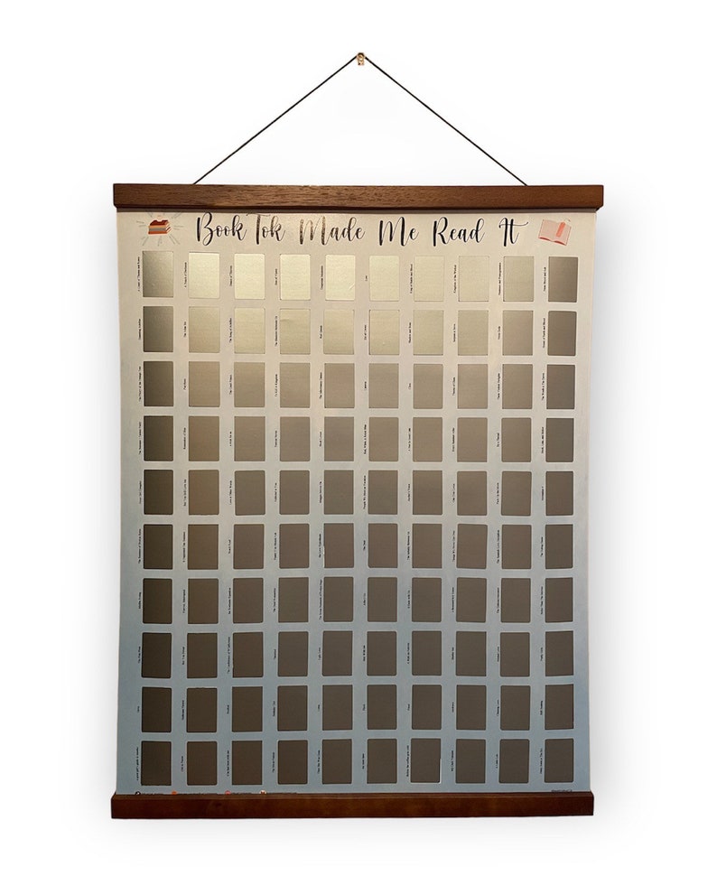 May include: A white poster with a wooden frame and a black string for hanging. The poster has a grid of 100 squares, each with a different shade of grey. The poster has the text "Book Tok Made Me Read It" at the top.