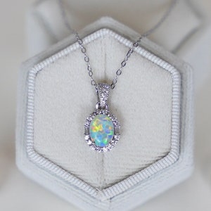 May include: A set of opal jewelry including a necklace, earrings, and a ring. The jewelry is silver with a white opal stone in each piece. The necklace is in a white box.