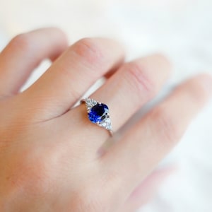 May include: A silver ring with a large oval blue sapphire surrounded by smaller clear diamonds.