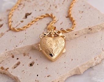 May include: A gold heart-shaped locket necklace with a rope chain. The locket is engraved with a floral design.
