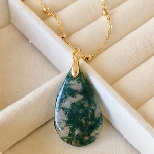 May include: A gold chain necklace with a teardrop-shaped green moss agate pendant. The pendant has a white and green marbled pattern.