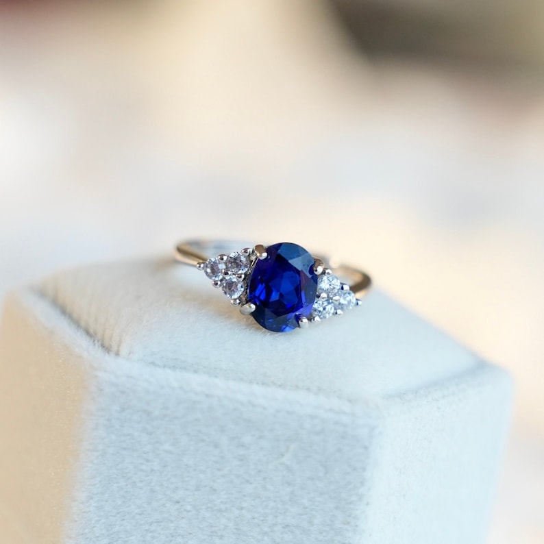 May include: A silver ring with a large blue sapphire gemstone surrounded by smaller white diamonds.