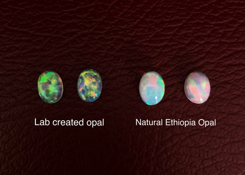 May include: Four oval-shaped opals, two lab-created and two natural Ethiopian opals. The lab-created opals have a green and blue iridescent sheen, while the natural opals have a more muted pink and blue sheen. The text "Lab created opal" and "Natural Ethiopia Opal" is printed below the opals.