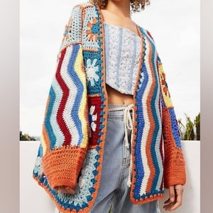 May include: A colorful crochet cardigan with a patchwork design featuring stripes, flowers, and geometric patterns in shades of blue, red, orange, yellow, and white.