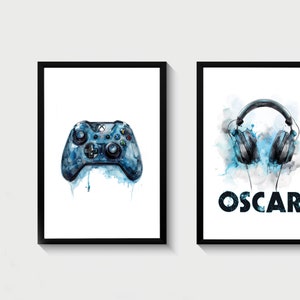 May include: Two framed prints, one with a blue watercolor illustration of a video game controller and the other with a blue watercolor illustration of headphones and the word "OSCAR" in black.
