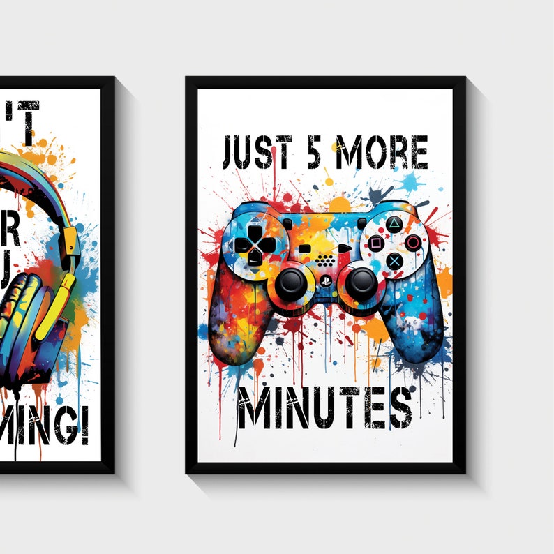 Puede incluir: Dos impresiones enmarcadas con un tema de juego. La primera impresi&oacute;n presenta unos auriculares con salpicaduras de pintura de colores. La segunda impresi&oacute;n presenta un mando de videojuego de colores con el texto "JUST 5 MORE MINUTES".