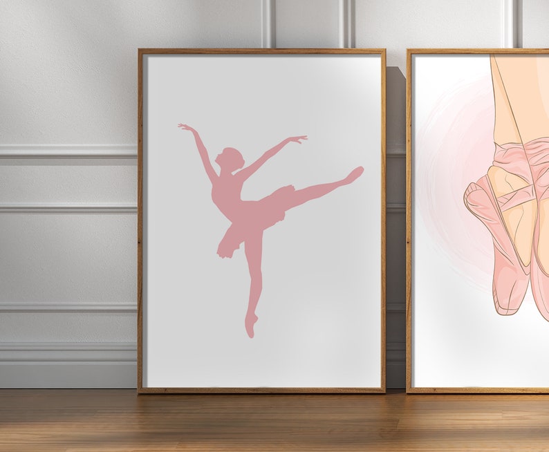 May include: Two framed art prints. The left print features a pink silhouette of a ballerina in a graceful pose. The right print shows a close-up of pink ballet pointe shoes. Both prints have a white background and are in wooden frames.