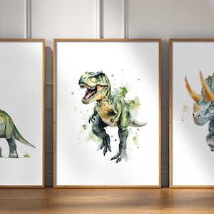 Pode incluir: Tr&ecirc;s pinturas de aquarela emolduradas de dinossauros. A pintura do centro apresenta um Tyrannosaurus Rex verde com um fundo branco e respingos de aquarela verde. A pintura &agrave; esquerda apresenta um dinossauro verde com um pesco&ccedil;o e uma cauda longos. A pintura &agrave; direita apresenta um Triceratops azul com um fundo branco e respingos de aquarela amarela.