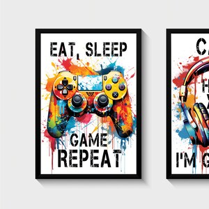 Puede incluir: Dos impresiones enmarcadas con un tema de juego. La primera impresi&oacute;n presenta un mando de videojuego colorido con el texto "Comer, dormir, jugar, repetir". La segunda impresi&oacute;n presenta unos auriculares con el texto "No te oigo, estoy jugando".