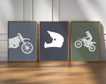 May include: Three framed prints with a motocross theme. The left print features a white silhouette of a dirt bike on a blue background. The center print features a white silhouette of a motocross helmet on a blue background. The right print features a white silhouette of a dirt bike with a rider on a green background.