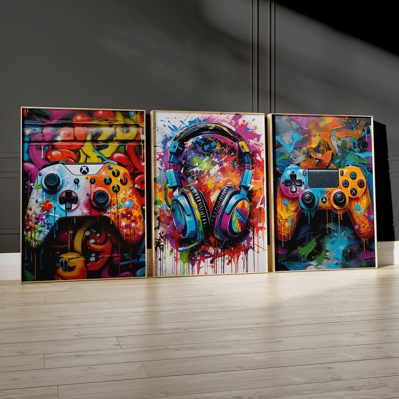 Pu&ograve; includere: Tre stampe su tela incorniciate colorate con un tema da giocatore. La stampa a sinistra presenta un controller per videogiochi bianco con accenti colorati su uno sfondo di graffiti. La stampa al centro presenta un paio di cuffie blu e viola con schizzi di vernice colorati. La stampa a destra presenta un controller per videogiochi giallo e blu con accenti colorati su uno sfondo di graffiti.
