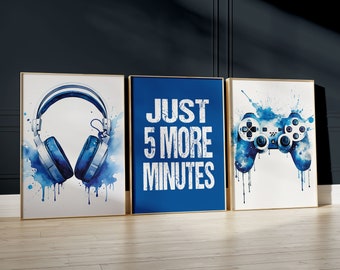 Pode incluir: Três impressões de arte emolduradas com designs em aquarela. Uma apresenta fones de ouvido azuis, outra diz "JUST 5 MORE MINUTES" em branco sobre azul, e a terceira mostra um controle de videogame azul. Todas estão em molduras douradas.