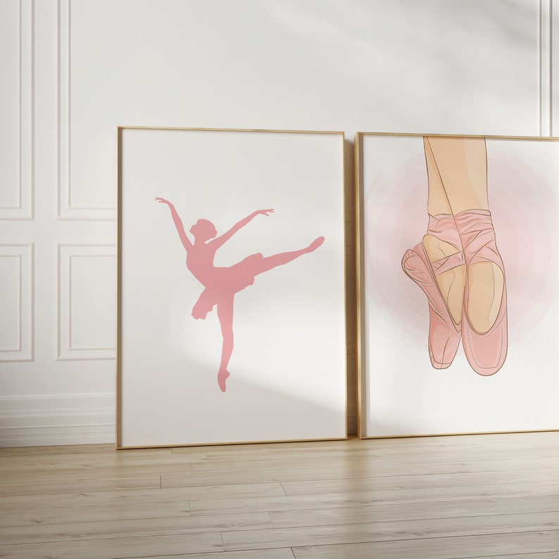 May include: Two framed art prints featuring ballet themes. One print shows a pink silhouette of a ballerina in a graceful pose. The other print depicts a pair of ballet shoes with pink ribbons against a soft pink background.