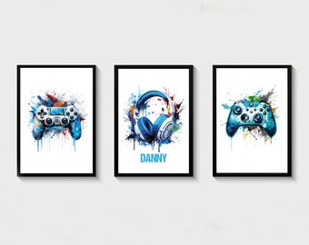 May include: Three framed prints with a white background and colorful watercolor splatters. The prints feature a video game controller, a pair of headphones, and a second video game controller. The middle print has the name "DANNY" written in blue.