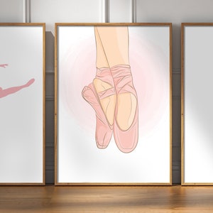 May include: Set of three framed art prints featuring ballet-themed illustrations. The central print showcases a pair of pink pointe shoes, while the flanking prints depict ballet dancers in silhouette. The artwork is set against a white background.
