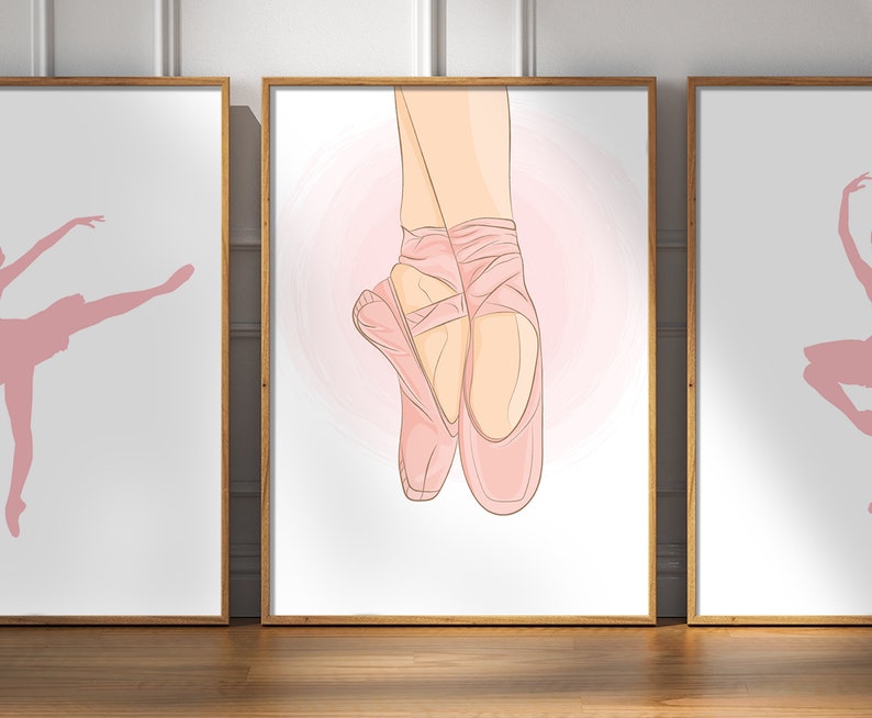 May include: Set of three framed art prints featuring ballet-themed illustrations. The central print showcases a pair of pink pointe shoes, while the flanking prints depict ballet dancers in silhouette. The artwork is set against a white background.