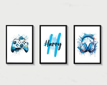 Pode incluir: Três impressões emolduradas com respingos de aquarela azul. A impressão da esquerda apresenta um controlador de videogame azul e branco. A impressão do meio tem o nome "Harry" em texto preto. A impressão da direita apresenta fones de ouvido azuis com detalhes brancos.