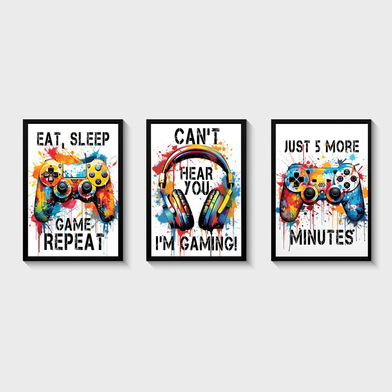 Puede incluir: Tres impresiones enmarcadas con salpicaduras de pintura coloridas y texto con tem&aacute;tica de juegos. La primera impresi&oacute;n dice "Comer, dormir, jugar, repetir" y presenta un mando de videojuego colorido. La segunda impresi&oacute;n dice "No puedo o&iacute;rte, &iexcl;estoy jugando!" y presenta unos auriculares coloridos. La tercera impresi&oacute;n dice "Solo 5 minutos m&aacute;s" y presenta un mando de videojuego colorido.