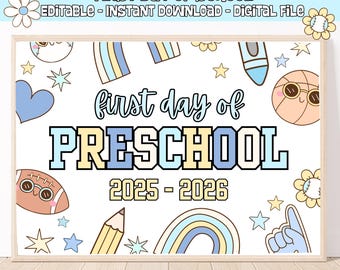 May include: A framed sign with the text "FIRST DAY OF SCHOOL" and "PRESCHOOL 2025-2026". The sign has a white background with cartoon illustrations of a flower, stars, a heart, a crayon, a basketball, a football, a pencil, and a rainbow.
