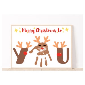 May include: A white card with the text "Merry Christmas to" in red letters and two brown reindeer handprint crafts. The reindeer have red noses and antlers. The reindeer on the left is a "Y" and the reindeer on the right is a "U".