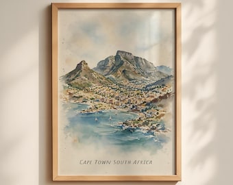 May include: A framed watercolor print depicting the Cape Town landscape with Table Mountain, the city coastline, and blue water with small sailboats. The text "CAPE TOWN SOUTH AFRICA" is printed in black at the bottom of the artwork.