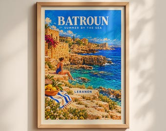 May include: A framed travel poster titled BATROUN SUMMER BY THE SEA LEBANON. The artwork depicts a coastal scene with a person in a blue swimsuit sitting on rocky cliffs overlooking the blue sea, with a basket of lemons and a striped towel.