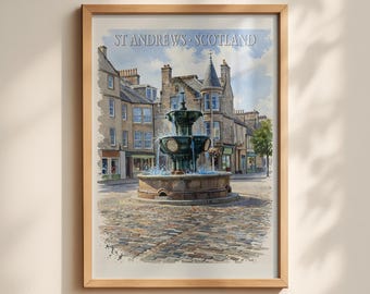 May include: A framed watercolor print of a town square in St Andrews, Scotland, featuring a central tiered stone fountain with flowing water, surrounded by historic stone buildings and a cobblestone street under a blue sky.