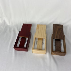 May include: Three wooden boxes with lids open, revealing a white interior. The boxes are made of different types of wood: mahogany, pine, and walnut.