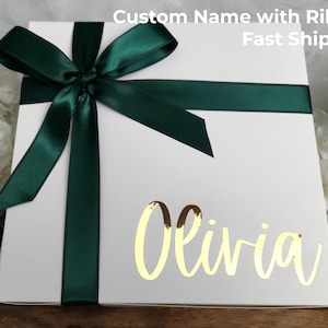 May include: A white gift box with a dark green satin ribbon and bow. The name "Olivia" is written in gold script on the box. Text at the top reads "Custom Name with Ribbon Fast Shipping".