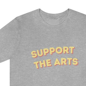 May include: A gray t-shirt with the text "SUPPORT THE ARTS" in yellow and red letters.