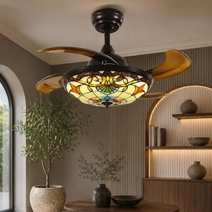 May include: A ceiling fan with a dark brown metal housing and retractable, translucent amber-toned blades. The central light fixture features a stained glass dome with a multi-colored floral pattern in shades of orange, blue, and cream.