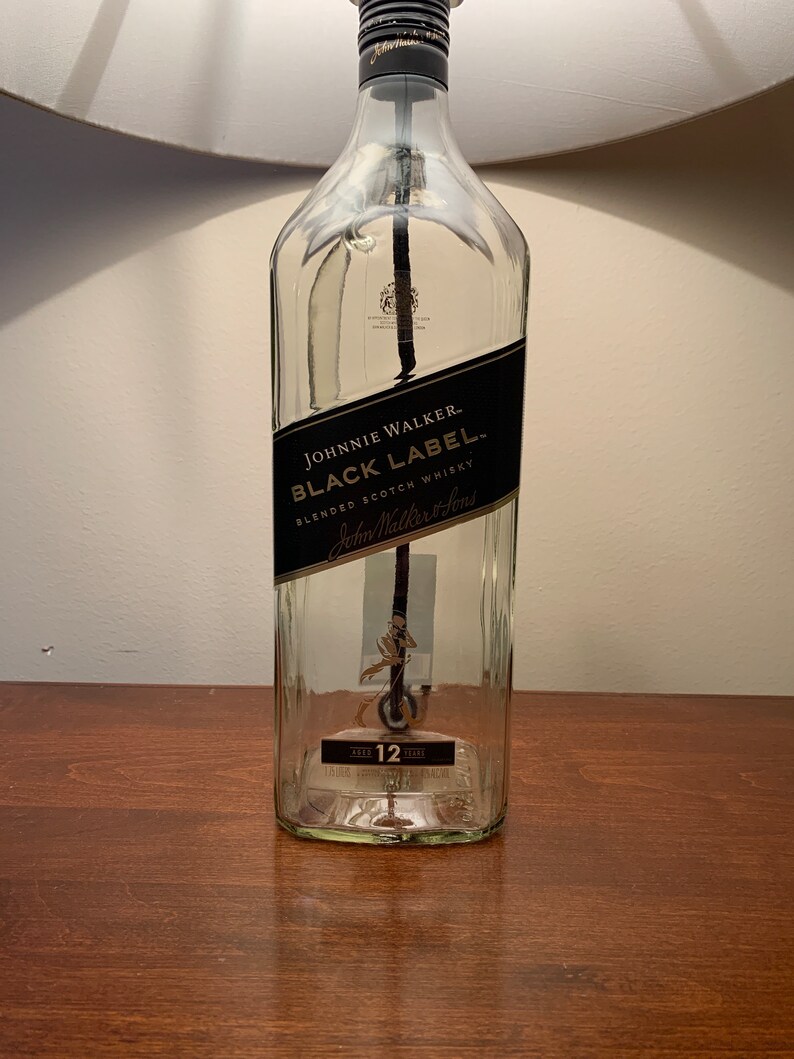 Puede incluir: Una botella de vidrio transparente con una etiqueta negra que dice "JOHNNIE WALKER BLACK LABEL BLENDED SCOTCH WHISKY John Walker & Sons" y una etiqueta dorada que dice "AGED 12 YEARS".