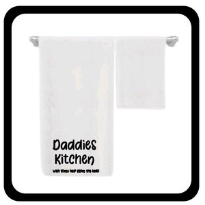 May include: White kitchen towel with the text "Daddies Kitchen" and the phrase "With some help from the kids!" printed in black.