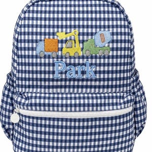 May include: A navy blue and white gingham backpack featuring an embroidered design of three construction vehicles in orange, yellow, and green. The name Park is embroidered in light blue thread below the vehicles. It has a front zippered pocket.
