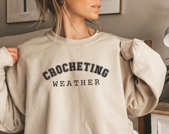 May include: A beige sweatshirt with the text "Crocheting Weather" in black.