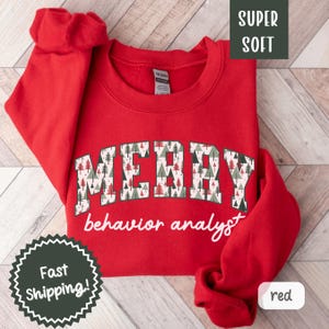 May include: Red Christmas sweatshirt with a green and white pattern that says "Merry behavior analyst".