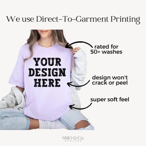 Op de afbeelding: Een lichtpaars t-shirt met de tekst "YOUR DESIGN HERE" in vette zwarte letters. Het shirt is geschikt voor meer dan 50 wasbeurten, met een ontwerp dat niet scheurt of loslaat en een superzacht gevoel heeft. De afbeelding bevat ook de tekst "We use Direct-To-Garment Printing".
