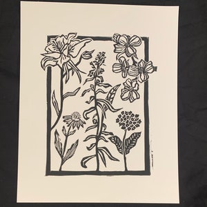 Puede incluir: Grabado en linóleo en blanco y negro de un arreglo enmarcado de varias flores, incluyendo lirios, equináceas y otras flores.