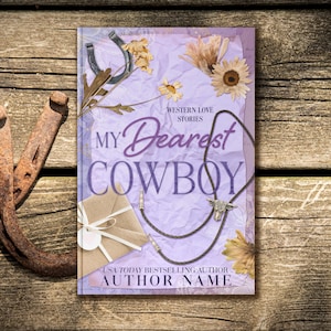 May include: A book cover with the title "My Dearest Cowboy" in a purple script font, with the subtitle "Western Love Stories." The cover features a horseshoe, dried flowers, and a bolo tie. The background is a light purple color with a rustic wooden texture.
