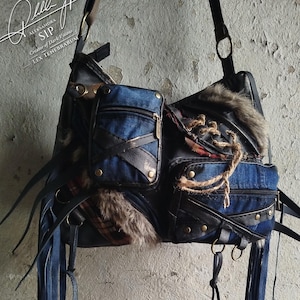 Może przedstawiać: Ręcznie robiona torba na ramię o unikalnym, mieszanym designie. Torba posiada dżinsowe kieszenie, skórzane akcenty, wykończenie ze sztucznego futra i długie dżinsowe frędzle. Torba ma czarny pasek na ramię i metalowe okucia. Torba ma tekst "Alessandra SIP" i "Lex Tenebrarum".