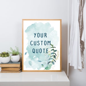 May include: A framed printable with a watercolor background in shades of blue and green. The text "YOUR CUSTOM QUOTE" is written in dark blue on the print. The print features a floral design with leaves and branches in shades of green and gold.