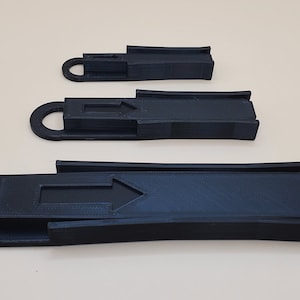 May include: Three black plastic ramps of different sizes with an arrow pointing to the right on each ramp. The ramps are designed for use with toy cars or other small objects.