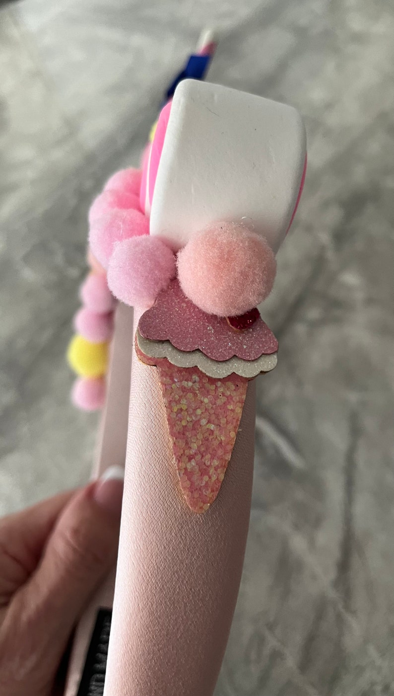 May include: Pink headband with a pink and white ice cream cone charm, pink pom poms, and a white marshmallow charm.