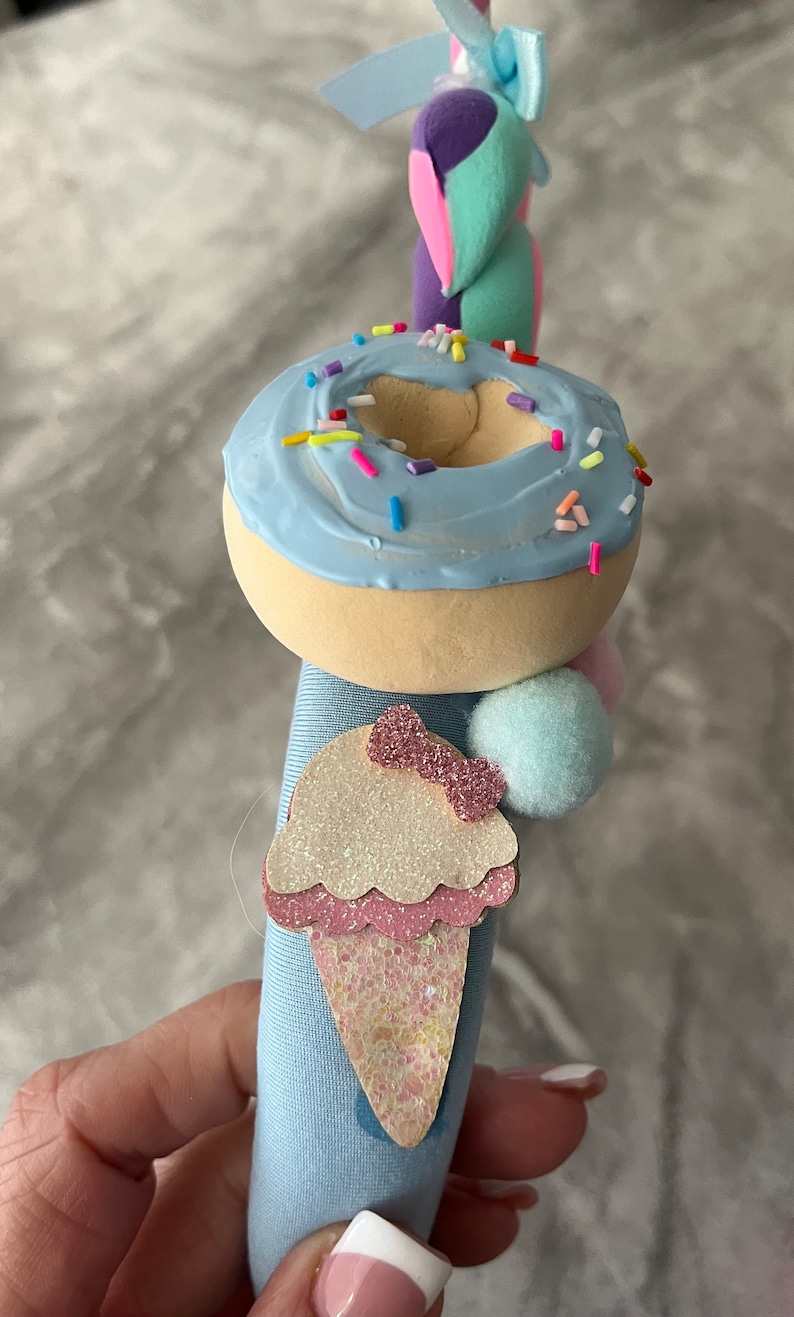 May include: A blue and white donut with colorful sprinkles, a blue and white ice cream cone with pink glitter, and a blue and white pom-pom on a blue fabric headband.