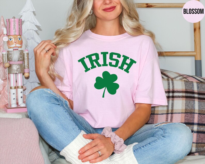 a woman sitting on a couch wearing a pink shirt with a shamrock on it
