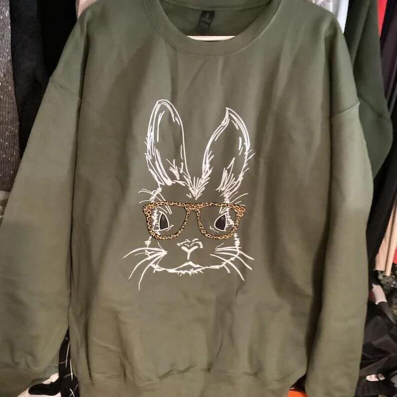 A green sweatshirt with a white illustration of a rabbit wearing glasses.