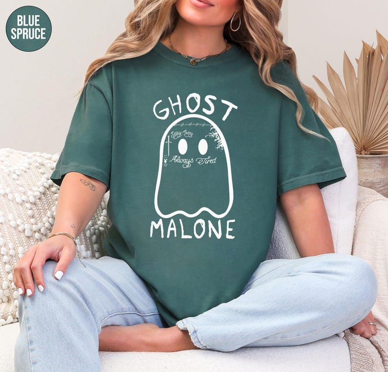 A woman wearing a green t-shirt with a ghost design and the text "GHOST MALONE" is sitting on a couch.