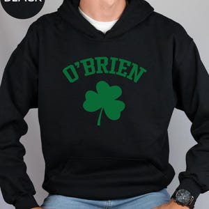 a man wearing a black hoodie with a shamrock on it