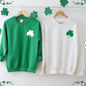 two green and white sweatshirts hanging on a wall