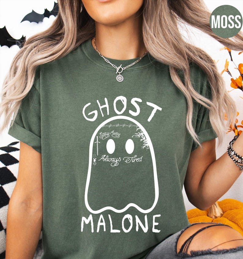 A woman wearing a green t-shirt with a graphic of a ghost and the text "GHOST MALONE" printed on it.